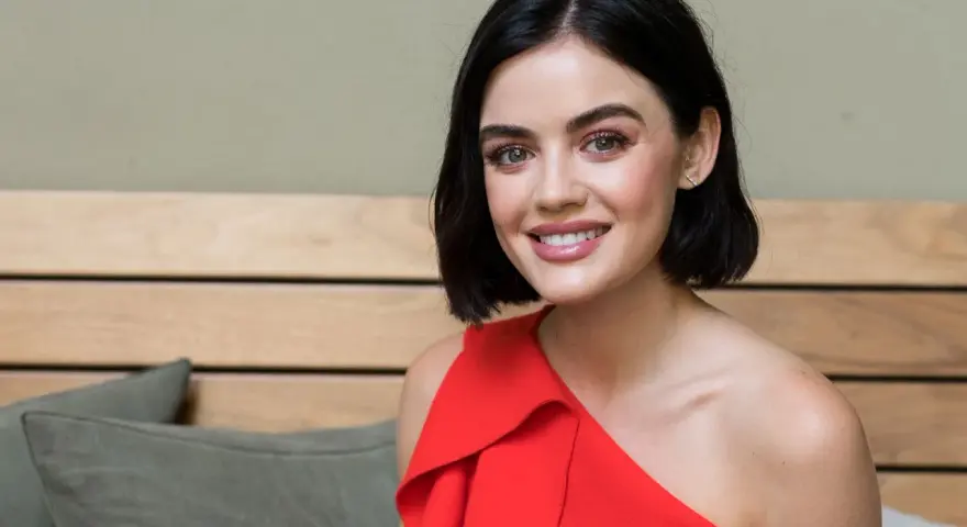 Lucy Hale sorride con un vestito rosso, ricordando i suoi film e programmi TV.