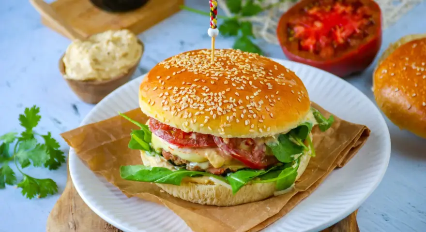 Un délicieux pain burger maison garni de légumes frais, de fromage fondant et d'une viande savoureuse. Un régal pour les yeux et les papilles !