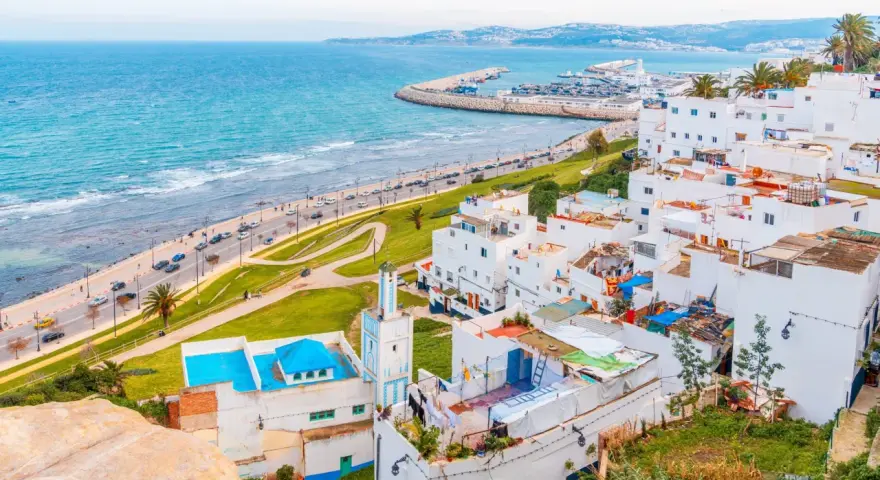 Widok na białe miasteczko z meczetem i turkusowym morzem, w oddali widać port. Tarifa Tanger prom.