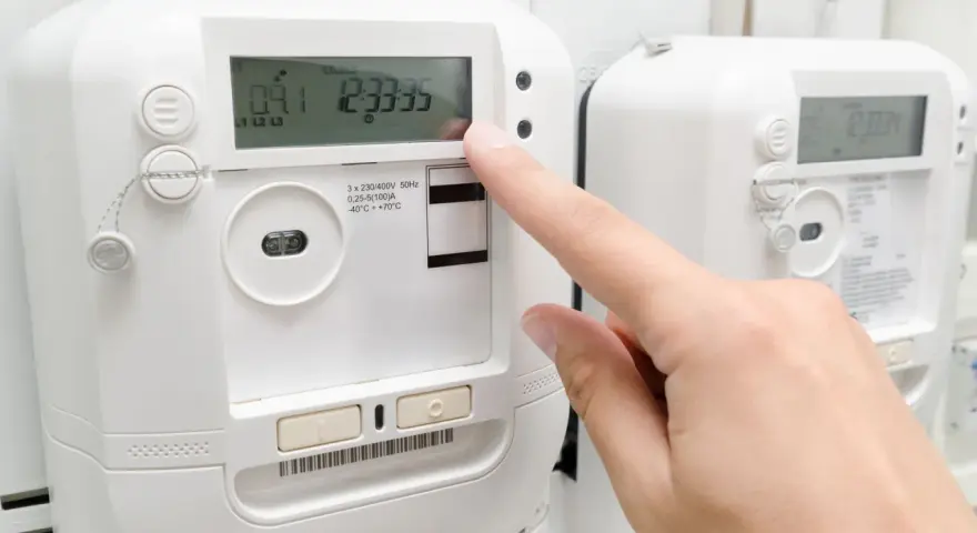 Palec naciska przycisk licznika energii elektrycznej, sprawdzając opłatę mocową.