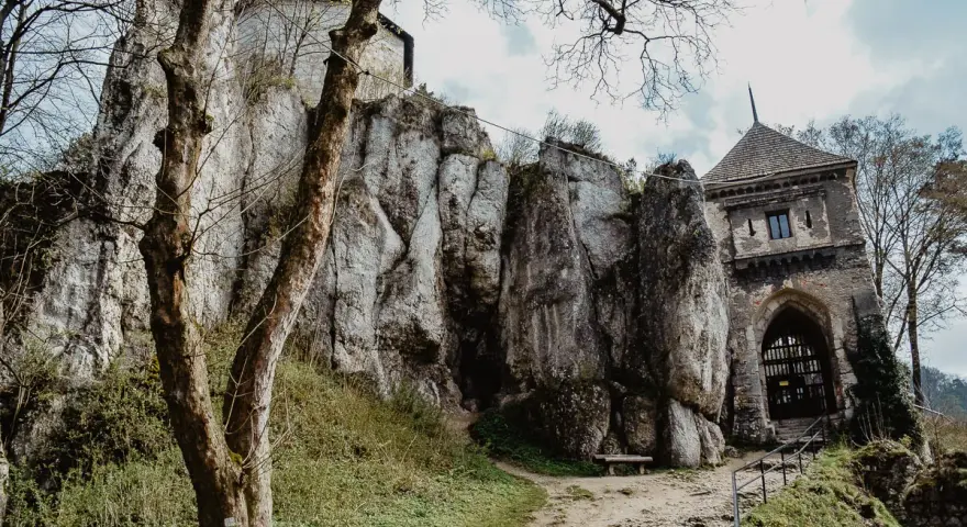 Ojcowski Park Narodowy atrakcje: ruiny zamku na skale, kamienna wieża bramna i ścieżka wśród zieleni.
