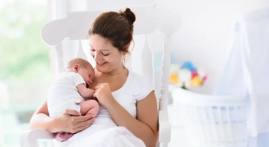 Uśmiechnięta mama kołysze śpiące dziecko. Gratulacje z okazji narodzin dziecka!