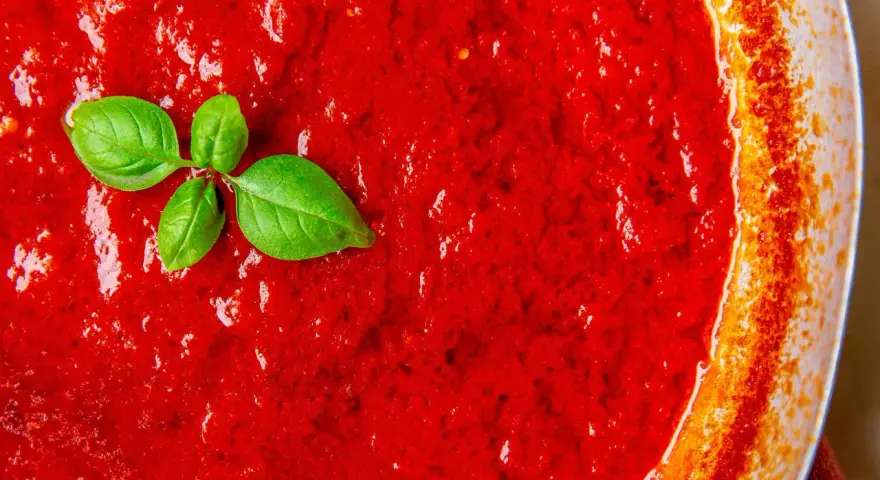 Leuchtend roter Sugo di Pomodoro mit frischen Basilikumblättern, bereit für Pasta.