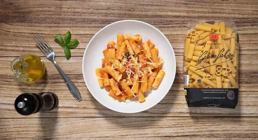 Macarrones a la napolitana servidos en un plato blanco, con un paquete de pasta Garofalo al lado.