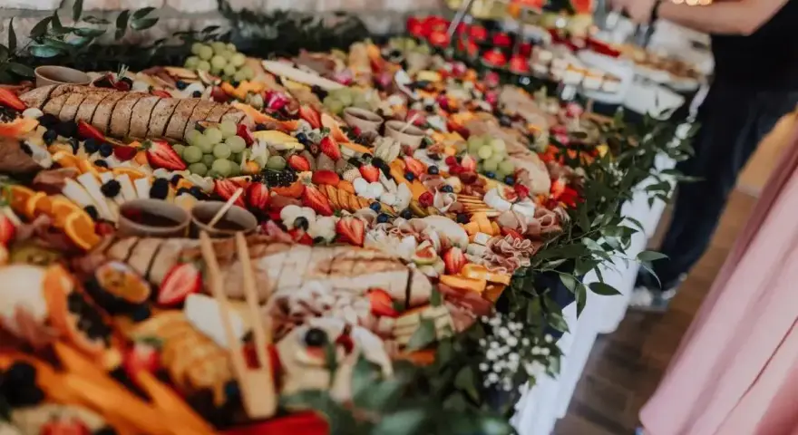 Stół pełen smakołyków na poprawiny: sery, wędliny, owoce, pieczywo i dipy. Idealna uczta po weselu.