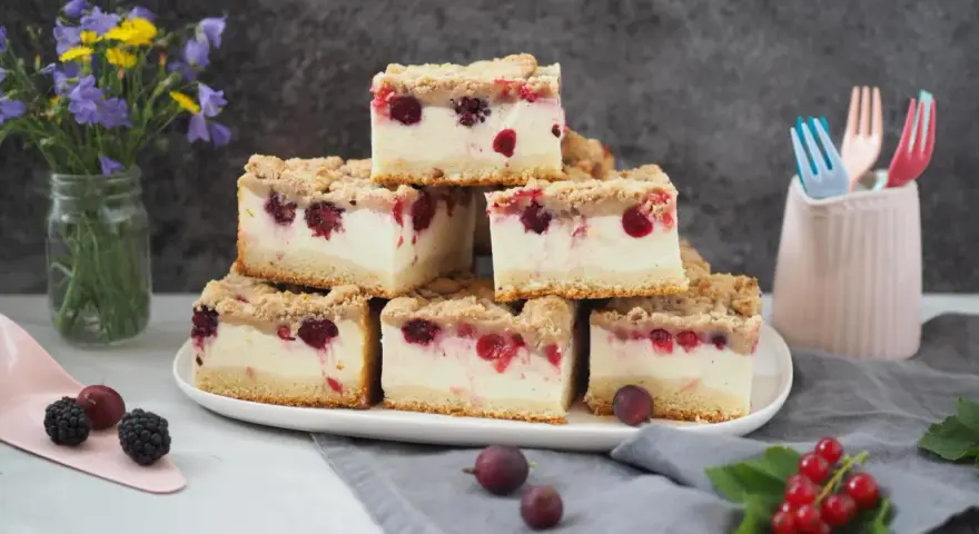 Stapel von saftigen Kuchenstücken mit Beeren und Streuseln – ein erfrischender Sommerkuchen, der Lust auf mehr macht.