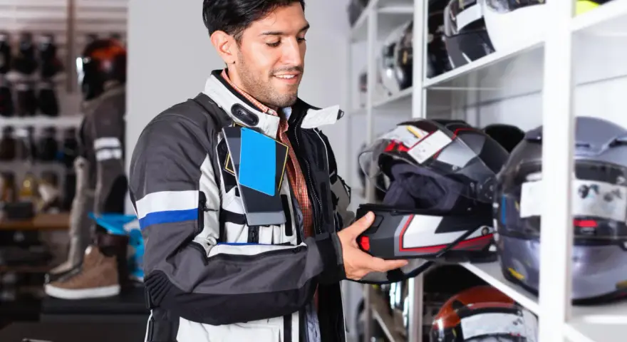 Uomo in negozio di moto esamina un casco, cercando la taglia XS. Corrisponde a una misura piccola, ideale per teste più minute.