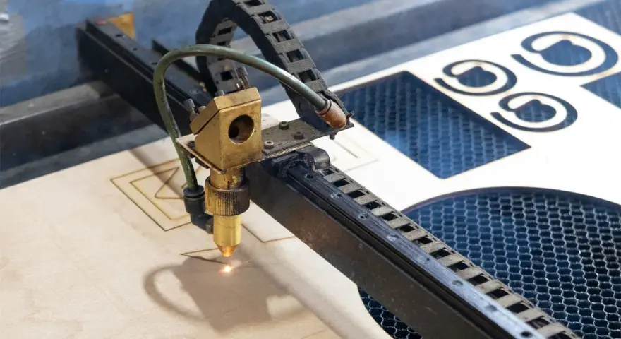 Macchina laser che sta per tagliare compensato, creando forme precise.