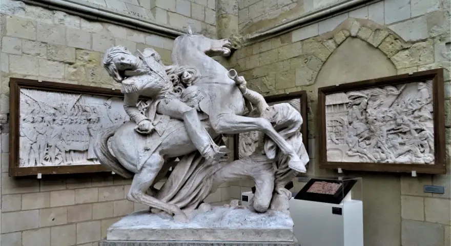 Sculpture équestre de David d'Angers, un homme en uniforme militaire sur un cheval cabré, avec des bas-reliefs en arrière-plan.
