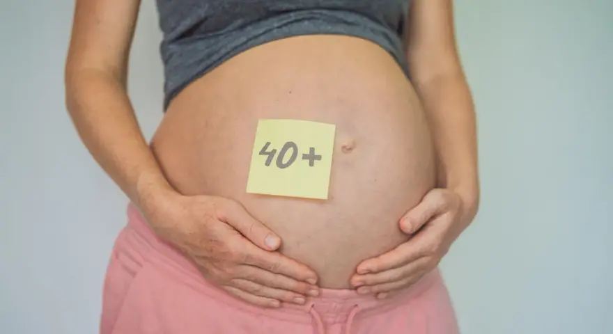 Brzuch kobiety w ciąży z karteczką "40+". To dowód, że ciąża po 40. jest możliwa i piękna.