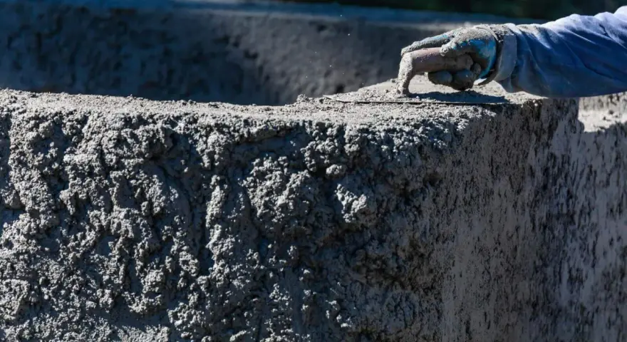 Ręka w rękawicy wygładza świeży beton. Zastanawiasz się, ile kosztuje worek cementu, by stworzyć coś takiego?