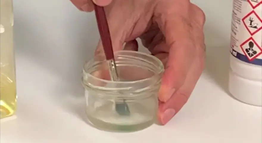 Pincel sumergido en un frasco con disolvente oleo, listo para limpiar.