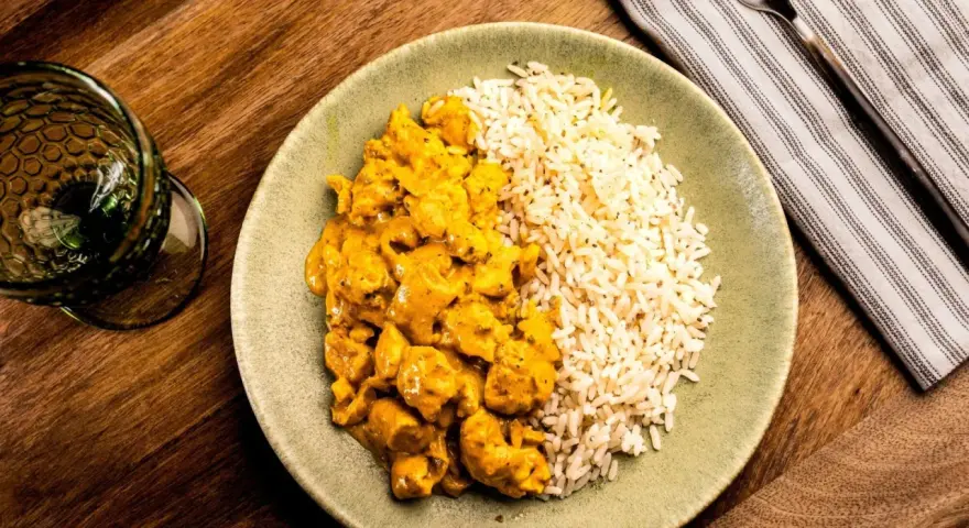 Plato de arroz con pollo en salsa curry, acompañado de arroz blanco. Un delicioso arroz con verduras y proteína.