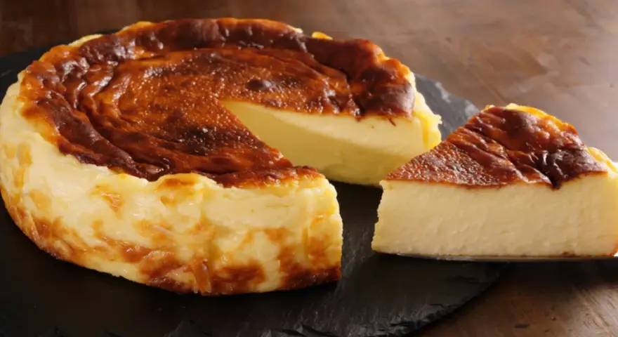 Pyszny, lekko przypieczony sernik na czarnej desce. Nawet jeśli sernik kcal kusi, warto spróbować!