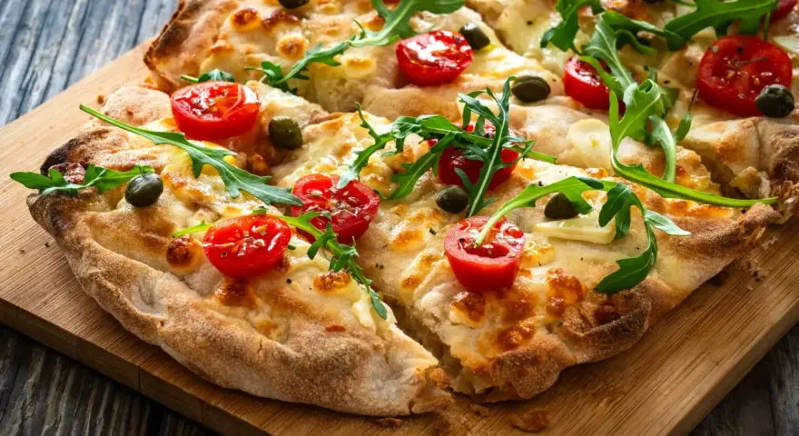 Pyszna pizza z pomidorkami, rukolą i kaparami. Idealne składniki na pizzę, które zachwycą każdego smakosza.