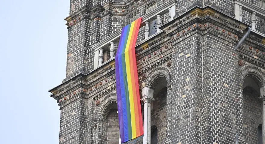 Regenbogenflagge hängt an einer Kirche. Die Bedeutung der Regenbogenflagge steht für Vielfalt und Akzeptanz.