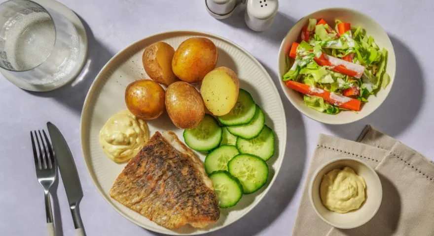 En tallrik med stekt vit fisk, kokt potatis, gurka och en klick majonnäs. Ett perfekt vit fisk recept för en snabb middag.