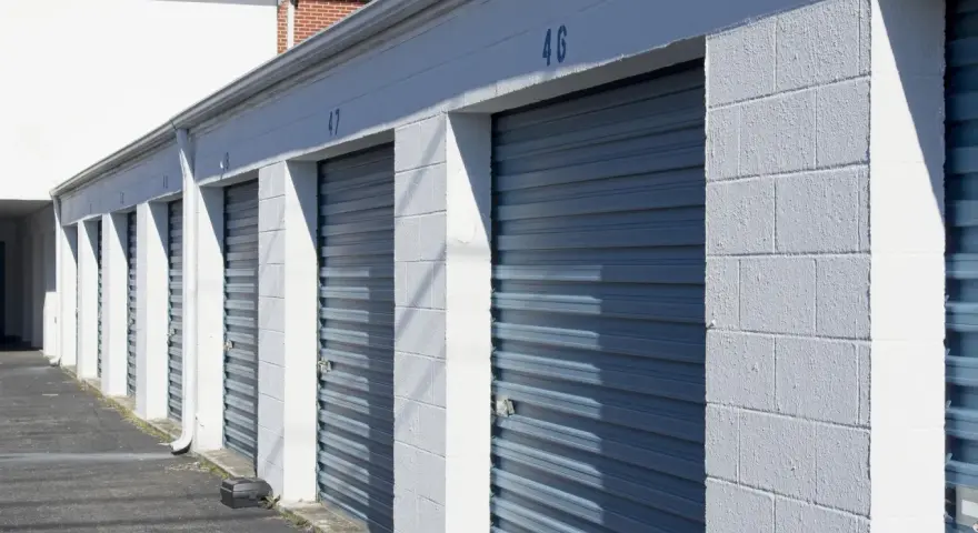 Rząd niebieskich, metalowych bram garażowych z numerami 46 i 47. Zastanawiasz się, ile kosztuje wynajem garażu?