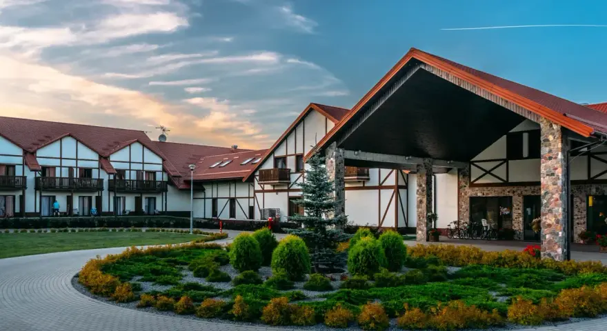 Elegancki hotel Mikołajki Spa z charakterystyczną architekturą i zadbanym ogrodem zaprasza na wypoczynek.