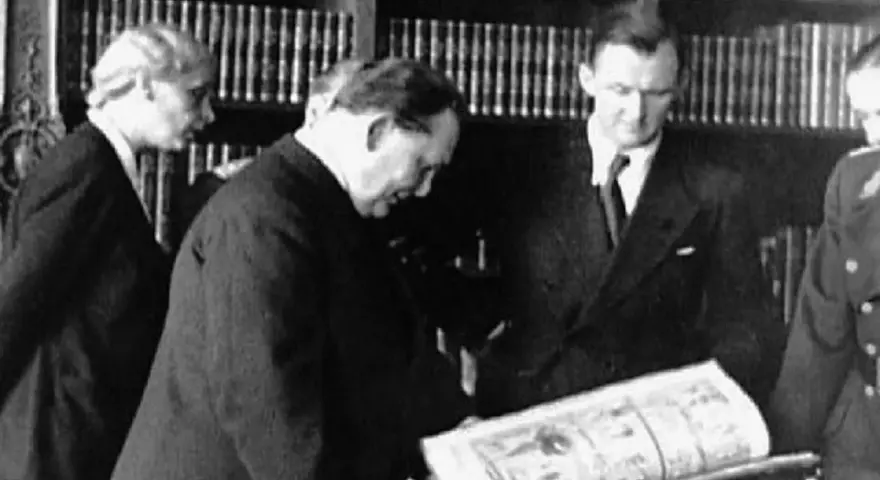 Bruno Lohse et d'autres hommes examinant un livre ouvert dans une bibliothèque.