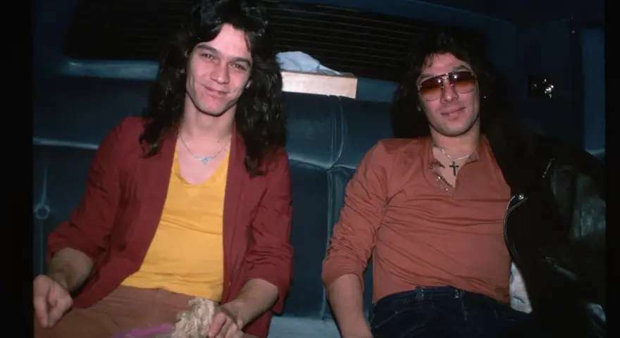 Alex Van Halen i jego brat Eddie Van Halen siedzą w samochodzie, obaj w stylowych ubraniach z lat 80.