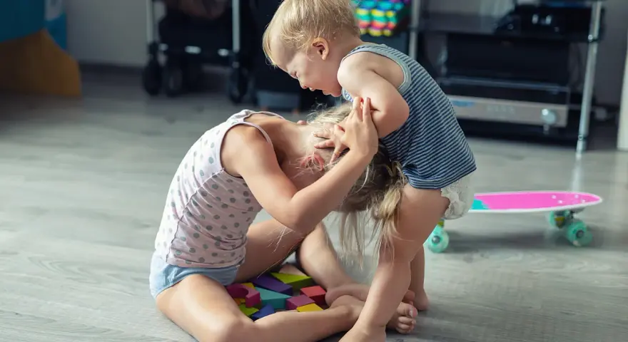 Kleinkind hält älteres Kind am Kopf fest. Was tun, wenn Kinder schlagen? Hier wird spielerisch gestritten.