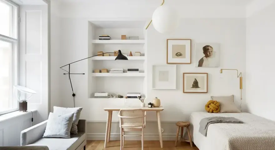 Accogliente camera da letto minimal con letto singolo, scrivania in legno, divanetto e quadri alle pareti.