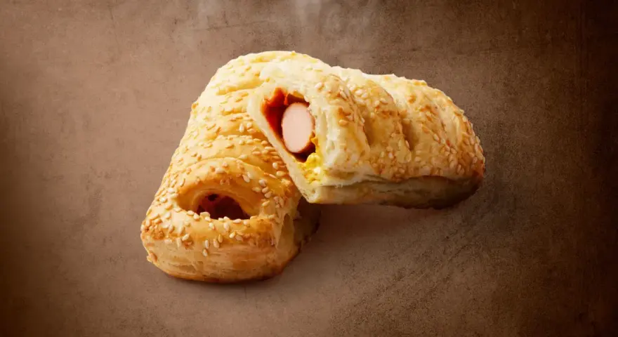 Pieczeni hot dog z Lidla, posypany sezamem, z widocznym parującym wnętrzem. Zastanawiasz się, ile kcal ma hot dog z Lidla?