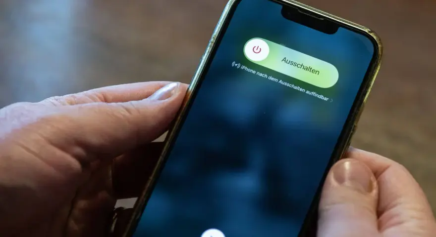 Hände halten ein iPhone mit dem Ausschaltmenü.