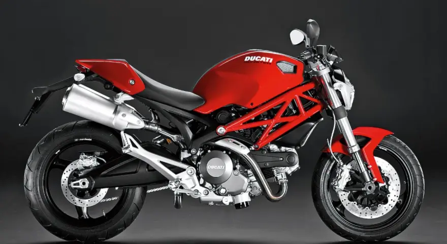 Czerwony Ducati Monster 696 z charakterystyczną kratownicową ramą, błyszczącym wydechem i sportowym siedzeniem.
