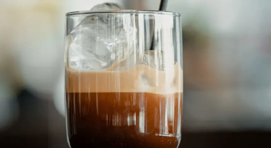 Orzeźwiające freddo espresso z lodem i pianką w szklance, gotowe do wypicia.