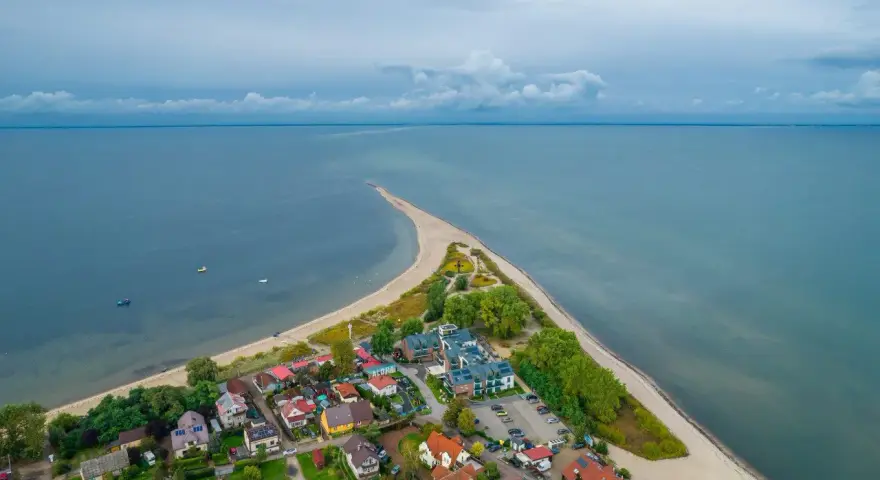 Malownicza miejscowość nad morzem, z domkami i plażą, wcinająca się w spokojne wody.