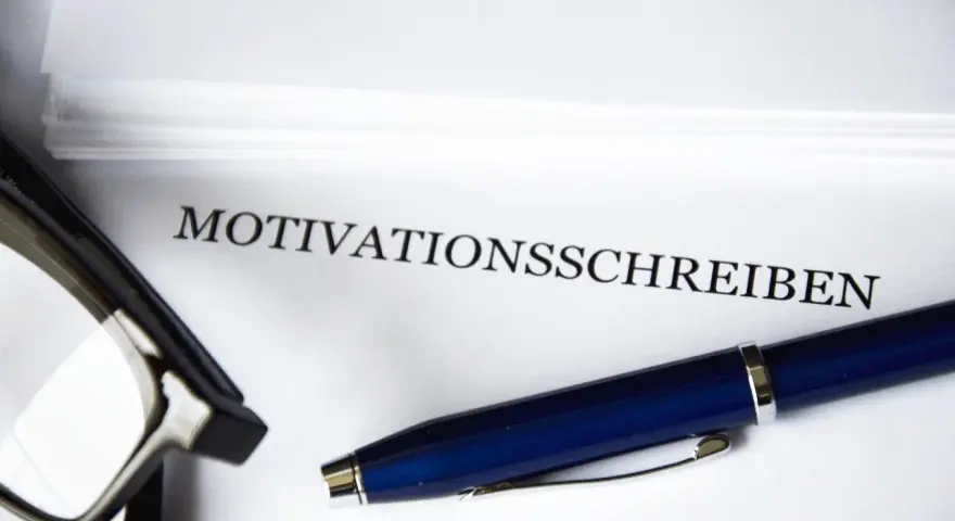 Okulary i długopis leżą obok dokumentu z napisem "MOTIVATIONSSCHREIBEN".