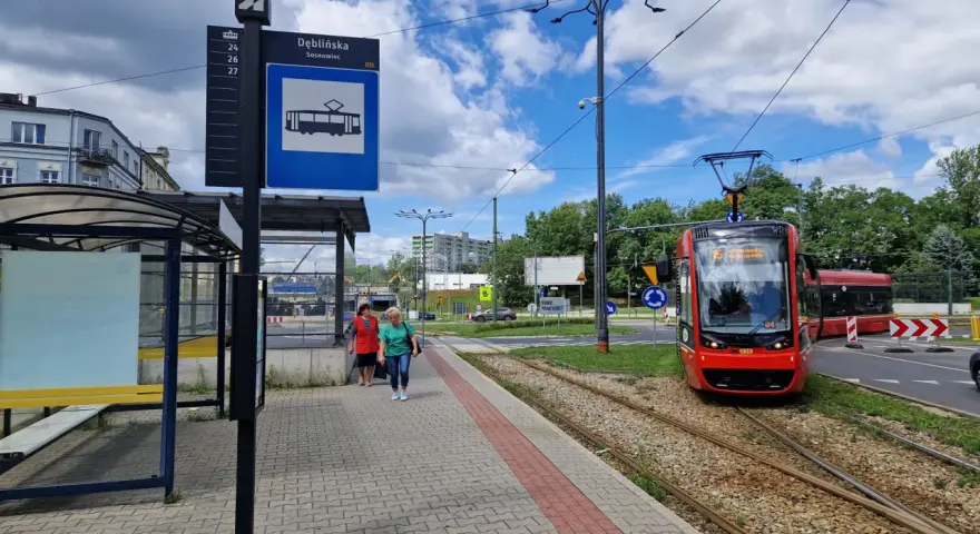 Przystanek Dęblińska w Sosnowcu. Tramwaj czeka na pasażerów, a rozkład jazdy MZK jest widoczny na słupie.