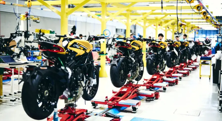 Linea di produzione MV Agusta: moto sportive gialle e nere in fase di assemblaggio su supporti rossi.