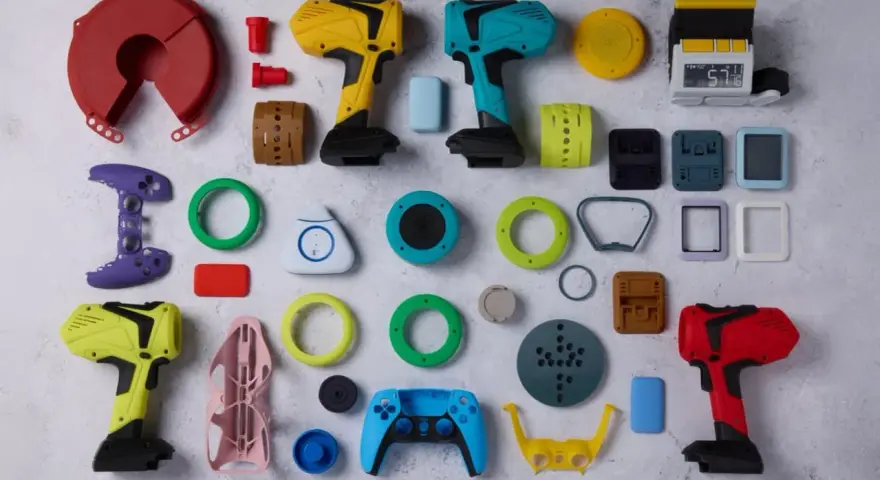 A vibrant collection of components, likely from a color resin 3D printer project, including tool-like objects, game controller parts, and various geometric shapes.