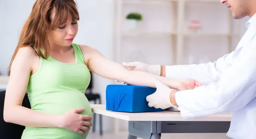 Lekarz pobiera krew od ciężarnej kobiety, aby sprawdzić poziom glukozy w ciąży.