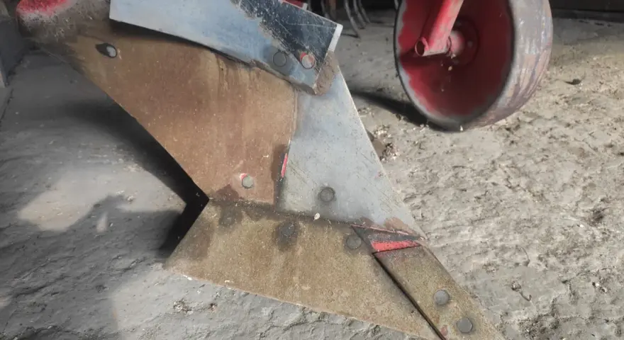 Metalowy lemiesz pługa, gotowy do pracy na polu. To właśnie on odwraca ziemię, przygotowując ją pod zasiew.