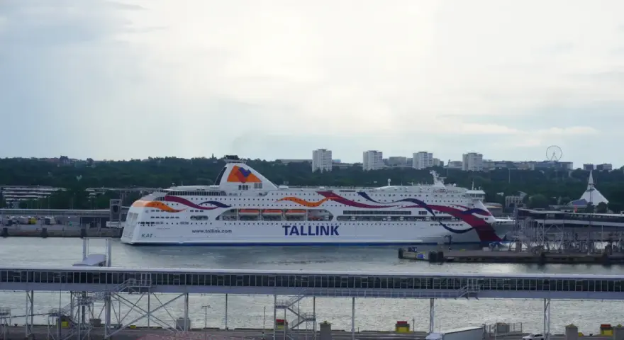 Prom Tallink płynie z Tallinna do Sztokholmu. Statek z kolorowymi pasami na burcie cumuje w porcie.