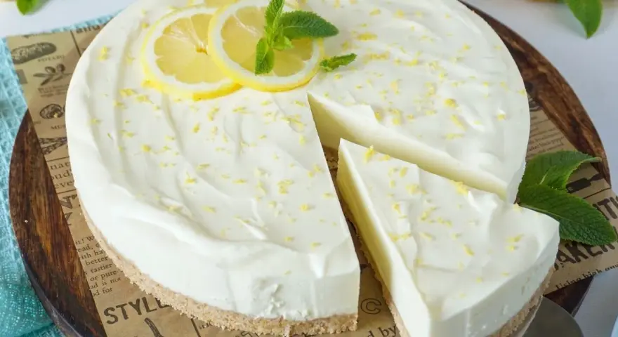 Cremige Philadelphia Torte mit Zitronenscheiben und Minze, ein Stück wurde bereits entnommen.