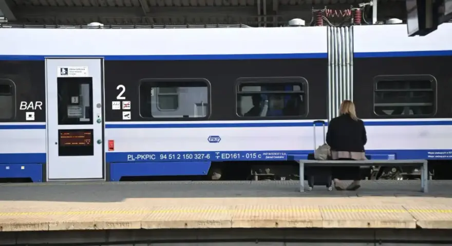 Kobieta z walizką czeka na pociąg PKP Intercity, szukając tanich biletów.