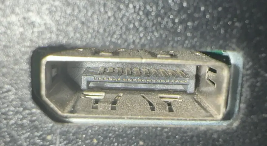 Närbild på ett dammigt displayport uttag med synliga kontakter och fästen.