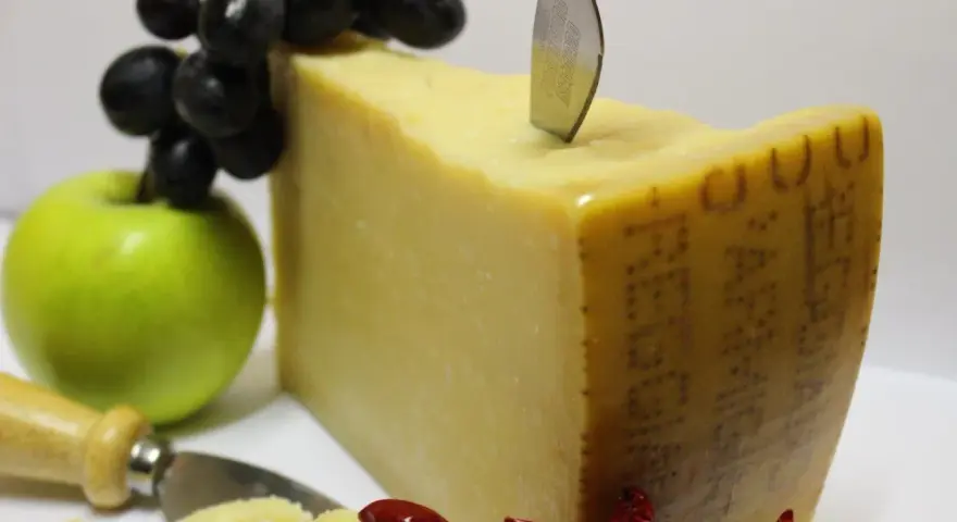 Ein Stück Parmigiano Reggiano mit Trauben, Apfel und Chilis. Verschiedene parmesan sorten sind hier schön arrangiert.