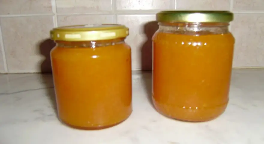 Due barattoli di marmellata di pesche fatti in casa, pronti per essere gustati.