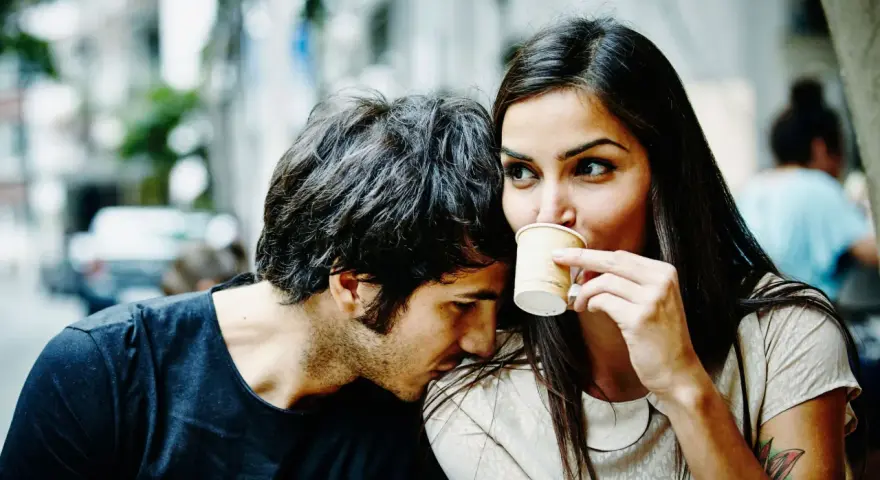 Un homme murmure à l'oreille d'une femme qui boit son café. Un tendre début de relation, peut-être le surnom qu'il vient de lui donner.