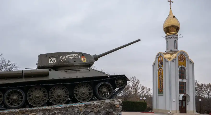 Czołg z napisem "Za Rodinu!" stoi obok cerkwi z złotą kopułą. Pomnik na nadniestrze.