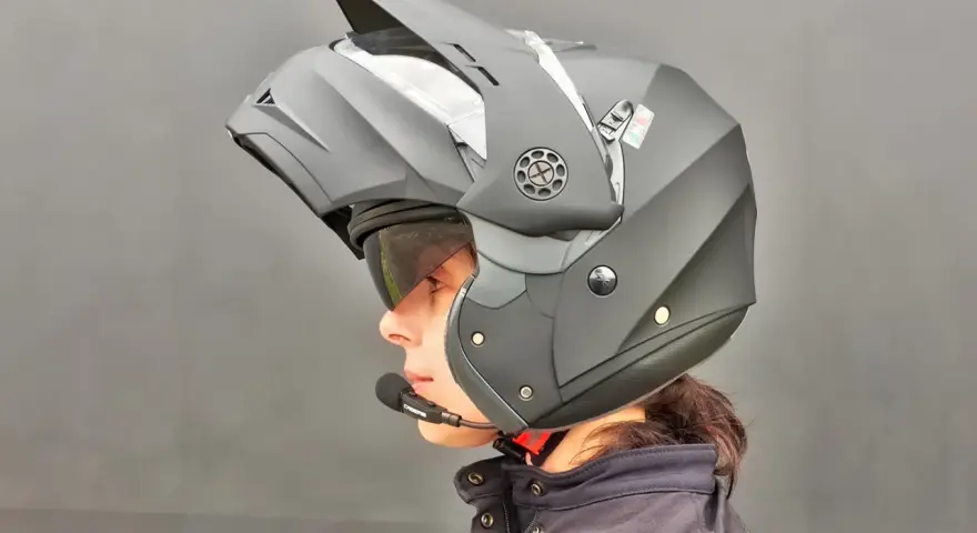 Profilo di una persona con casco da moto modulare nero, visiera sollevata e microfono. Guida sicura: come scegliere casco moto.