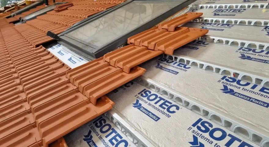 Tegole in laterizio su un tetto in costruzione, con lucernario e isolamento termoisolante ISOTEC.