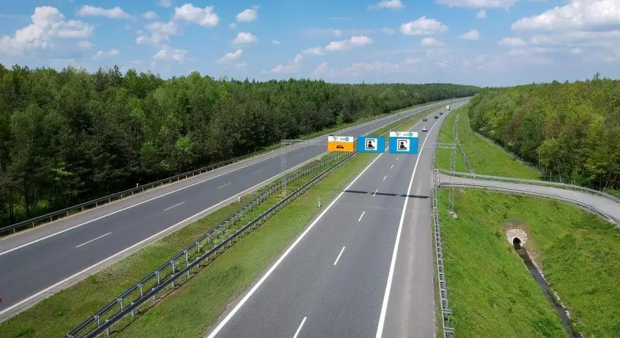 Znaki na autostradzie A4 informują, czy jest ona płatna. Widok na pustą autostradę w słoneczny dzień.