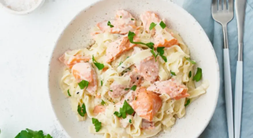 Pasta cremosa con trozos de salmón rosado y perejil fresco. Un plato delicioso y nutritivo.